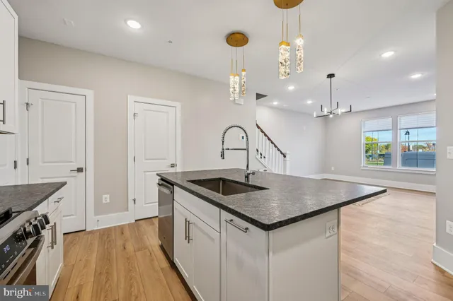 a kitchen that has a sink a microwave oven a stove and white cabinets with wooden floor