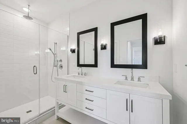a bathroom with a double vanity sink mirror and shower