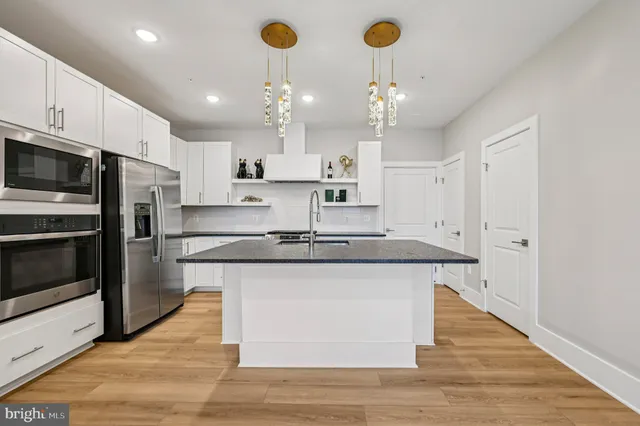 a large kitchen with stainless steel appliances granite countertop a sink a stove and a refrigerator