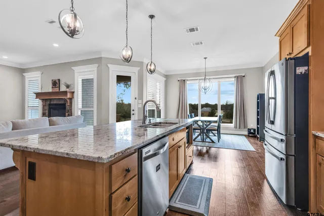 a kitchen with stainless steel appliances granite countertop a stove refrigerator and a wooden floor
