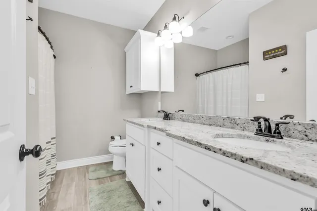 a bathroom with a granite countertop sink mirror and a toilet