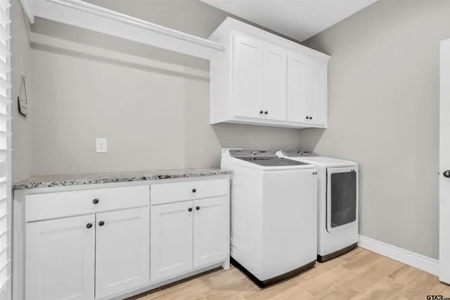 a utility room with granite countertop white cabinets and white appliances