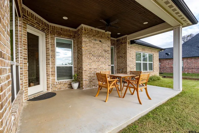 a patio with table and chairs and potted plants