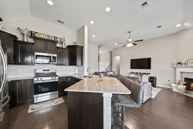 a kitchen with stainless steel appliances a stove sink microwave refrigerator and chairs