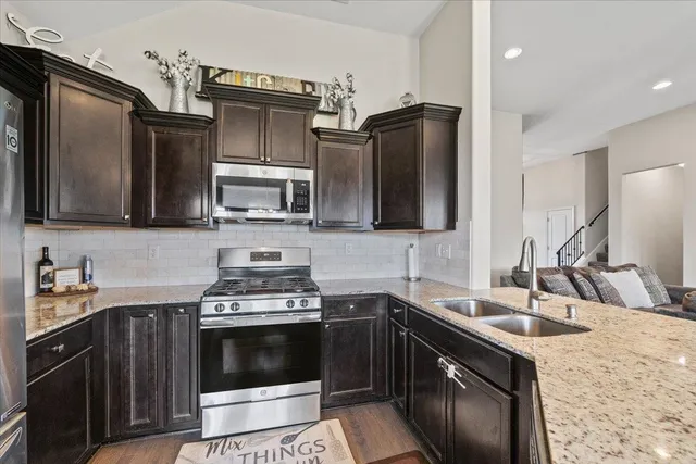 a kitchen with stainless steel appliances granite countertop a sink stove and refrigerator