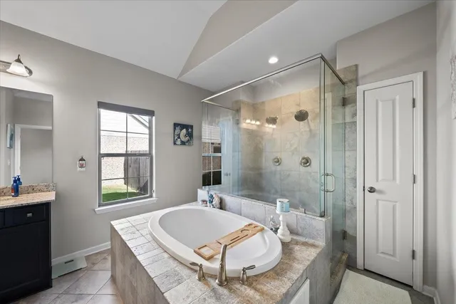a bathroom with a granite countertop sink a mirror a bathtub and shower