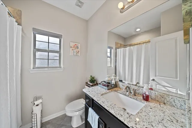a bathroom with a granite countertop sink a toilet and a mirror