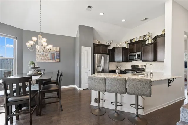 a kitchen with granite countertop a dining table chairs and a chandelier