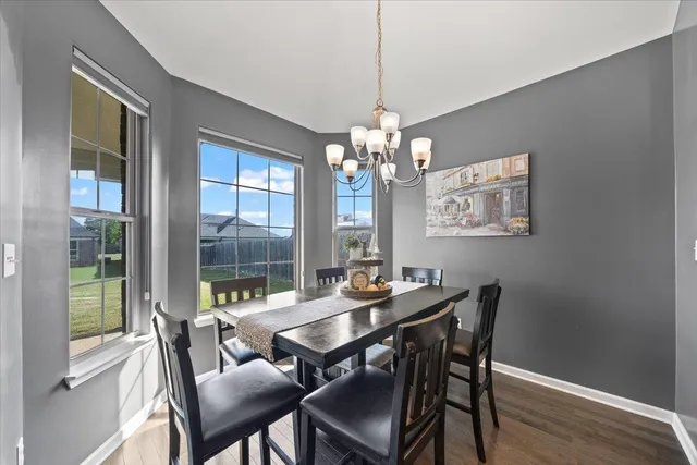 a dining room with wooden floor a chandelier a wooden table and chairs