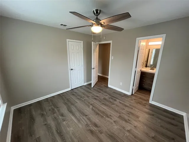 an empty room with wooden floor and ceiling fan