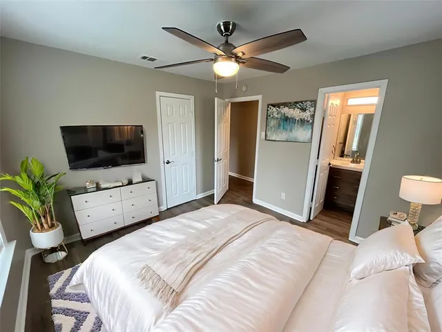 a bedroom with a bed a flat screen tv and a chandelier