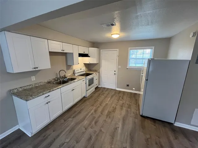 a large kitchen with a wooden floor and stainless steel appliances