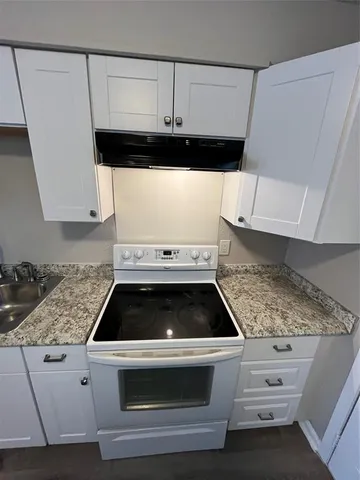 a kitchen with granite countertop white cabinets and white appliances