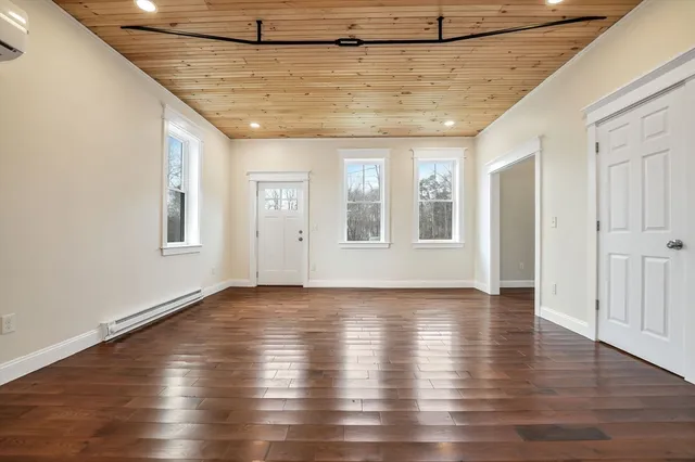 a view of an empty room with wooden floor and windows