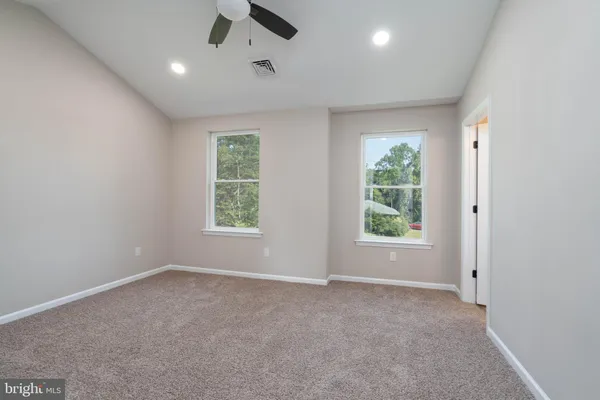 an empty room with windows and a ceiling fan
