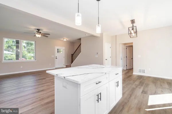 a hall with kitchen island a stove a wooden floor and a ceiling fan