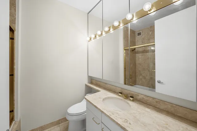 a bathroom with a granite countertop sink mirror vanity and toilet