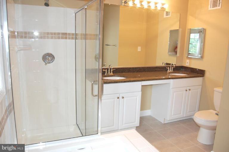 2306 Cavesson Court Reston, VA 20191 - Photo 22 of 28 a bathroom with a granite countertop sink a toilet a mirror and shower