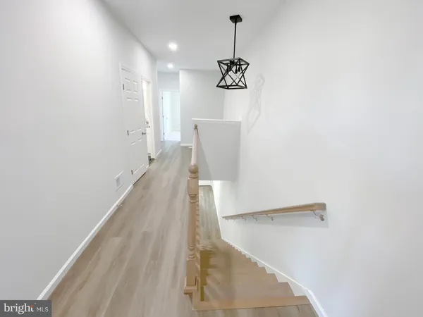 a view of a hallway with wooden floor and chandelier