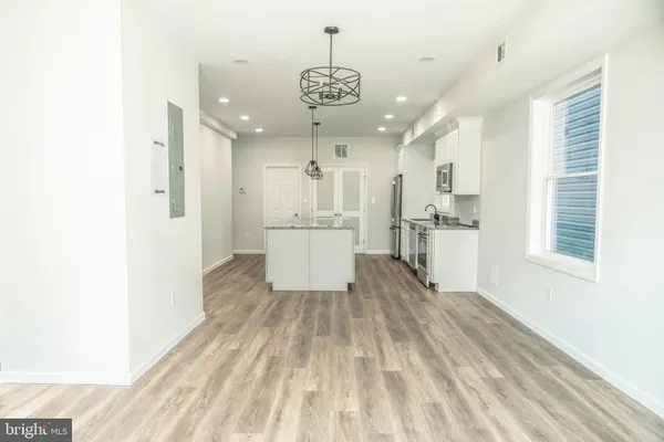 a view of a kitchen with a refrigerator an oven and white cabinets