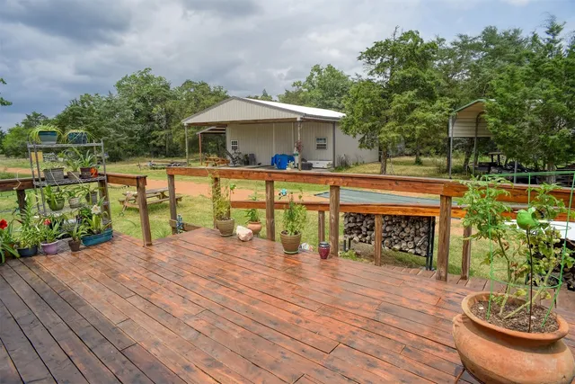 a view of a patio with table and chairs potted plants with wooden floor and fence