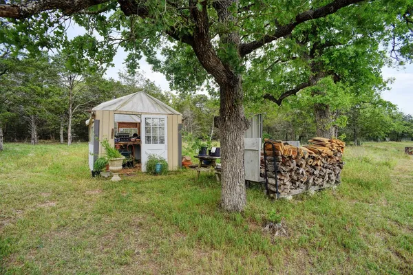 a view of a wooden house with a big yard and large trees
