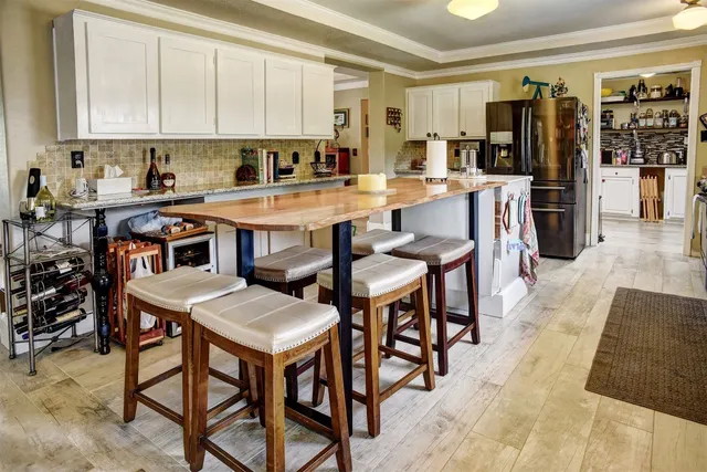 a kitchen with stainless steel appliances kitchen island granite countertop a table chairs sink and cabinets