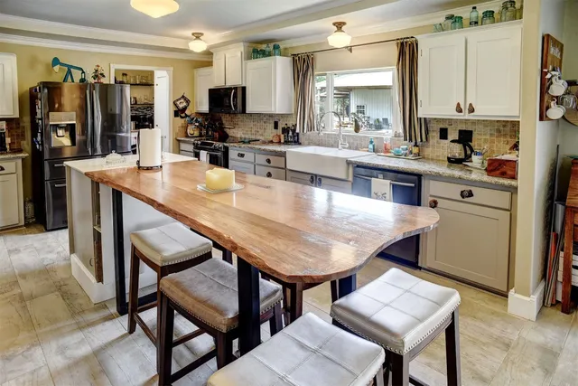 a kitchen with stainless steel appliances granite countertop a table chairs sink and cabinets