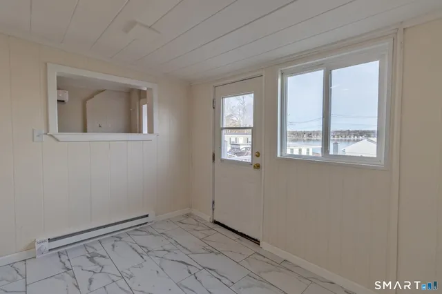 a view of an empty room with window and chandelier fan
