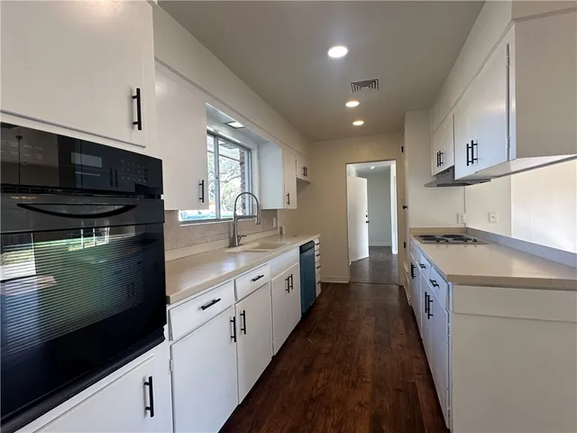 a large kitchen with stainless steel appliances kitchen island granite countertop a stove a sink and a microwave