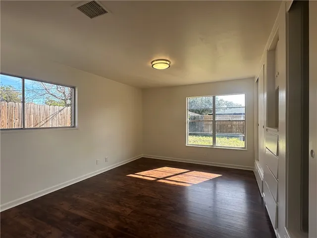 an empty room with wooden floor and windows