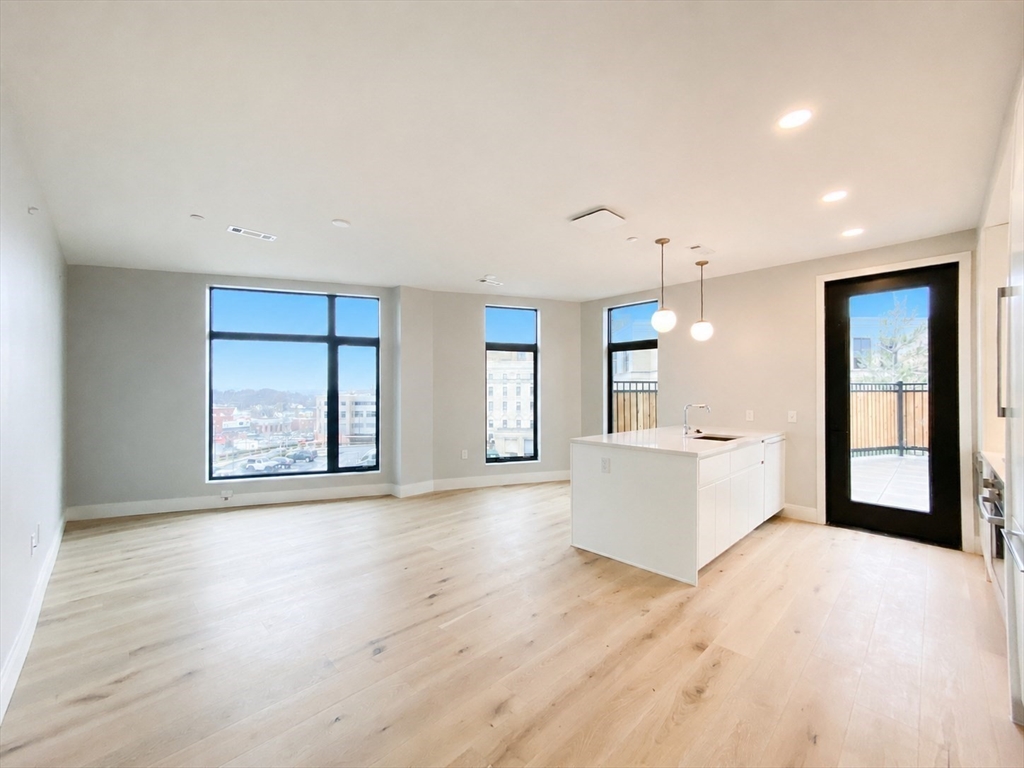 191 Washington Street, Unit 301 Boston, MA 02135 - Photo 6 of 40 an empty room with wooden floor and windows