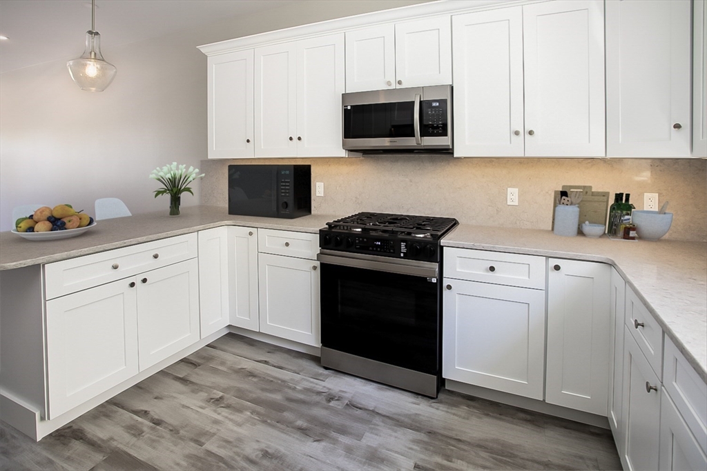 337 Danforth Street, Unit 7 Fall River, MA 02720 - Photo 11 of 28 a kitchen with granite countertop white cabinets sink and stainless steel appliances
