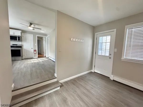 an empty room with wooden floor chandelier and windows