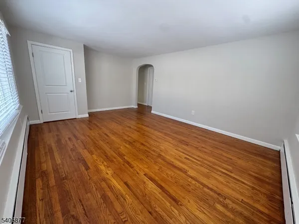 a view of empty room with window and wooden floor