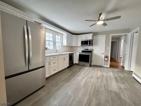 a large kitchen with cabinets wooden floor and stainless steel appliances