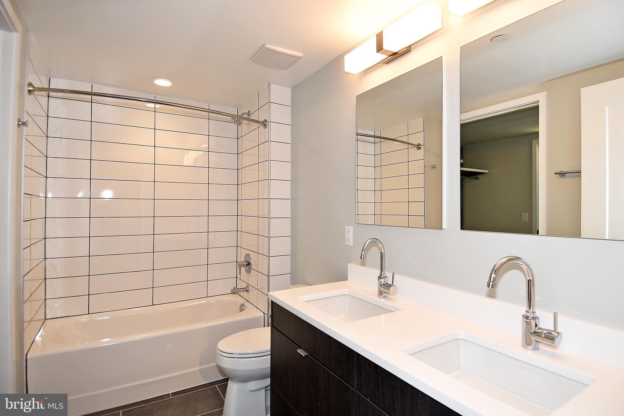 1300 4th Street Southeast, Unit 413 Washington, DC 20003 - Photo 20 of 47 a bathroom with a bathtub shower sink mirror vanity and toilet