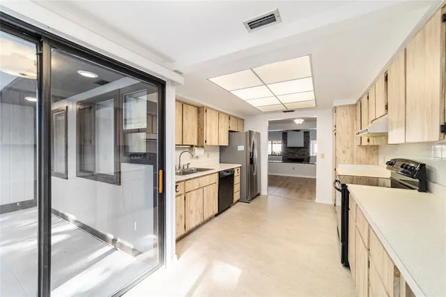 a kitchen with stainless steel appliances kitchen island granite countertop a refrigerator and a sink
