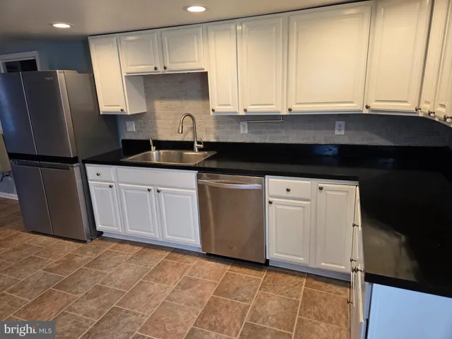 a kitchen with granite countertop white cabinets white stainless steel appliances and a sink