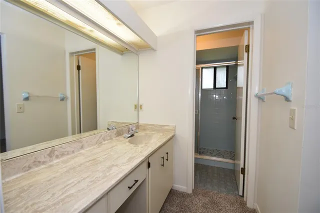 a bathroom with a granite countertop sink a mirror and a shower