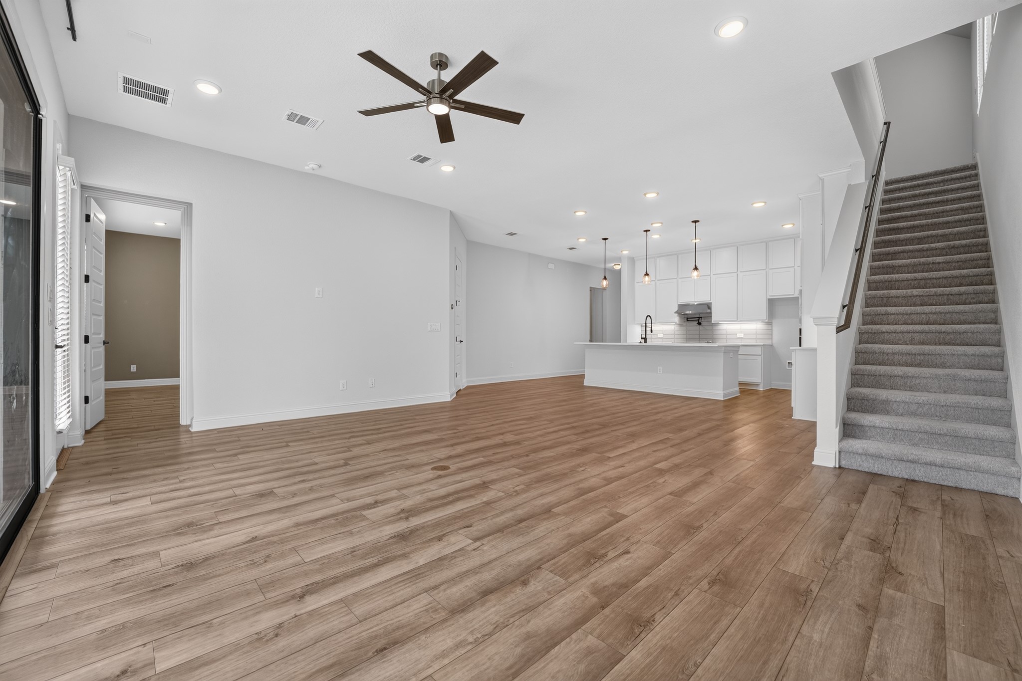 508 Pinnacle View Drive Georgetown, TX 78628 - Photo 4 of 27 An open-concept living space integrates a stylish kitchen, warm wood flooring, and a modern staircase.