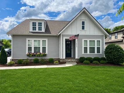 a front view of a house with a yard and green space