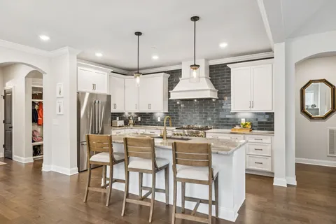 a kitchen with stainless steel appliances granite countertop a stove a refrigerator a oven a sink with a dining table and chairs