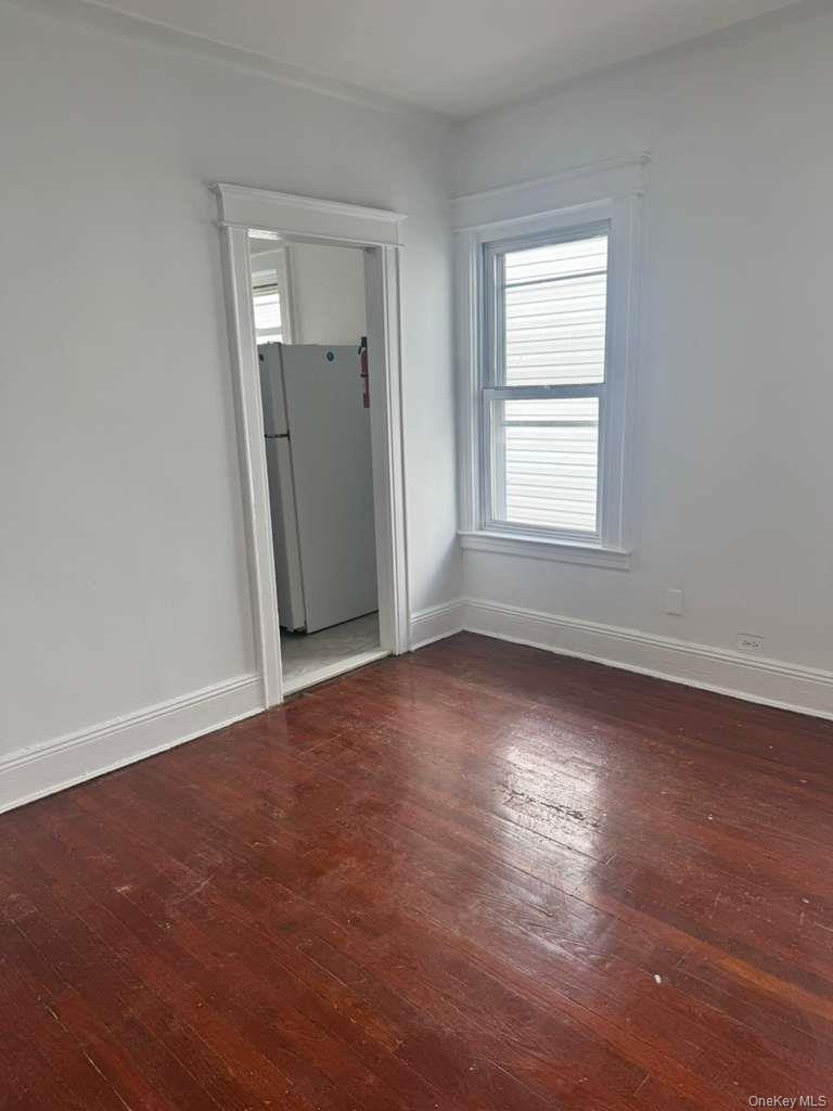 88-54 75th Street Queens, NY 11421 - Photo 3 of 14 an empty room with wooden floor and windows