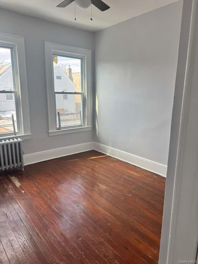 88-54 75th Street Queens, NY 11421 - Photo 8 of 14 an empty room with wooden floor and windows