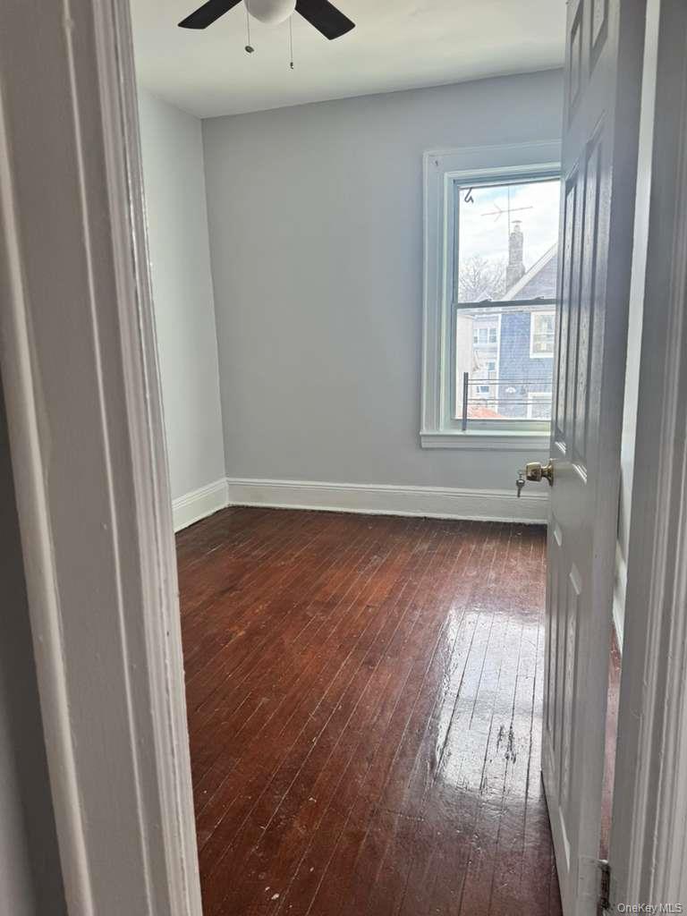 88-54 75th Street Queens, NY 11421 - Photo 9 of 14 an empty room with wooden floor and windows