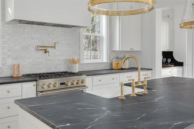 a kitchen with stainless steel appliances granite countertop a sink a stove and a wooden floors