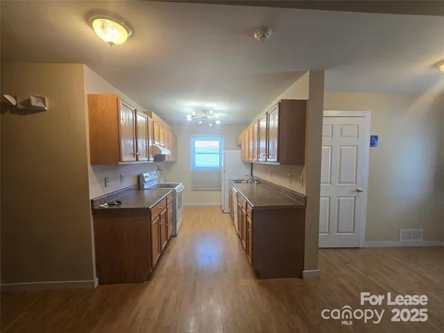 a kitchen with stainless steel appliances granite countertop a refrigerator a sink dishwasher a stove with wooden floor