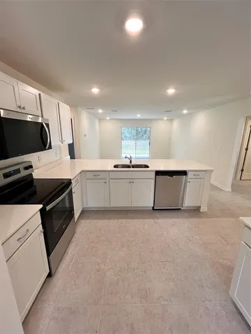 a large kitchen with a large counter top a sink stainless steel appliances and cabinets