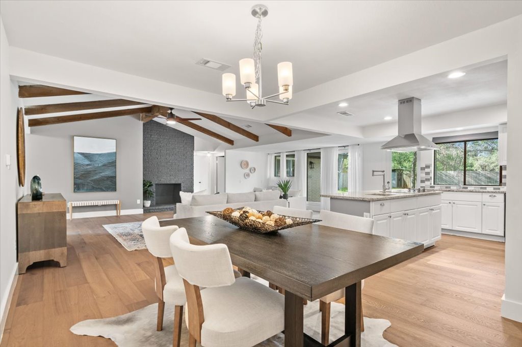 3402 Saddlestring Trail Austin, TX 78739 - Photo 5 of 33 Dining room with suspended lighting, light wood-style flooring, lofted ceiling with beams, a ceiling fan, and a large fireplace